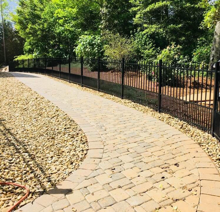 Black aluminum fence along a paver walkway