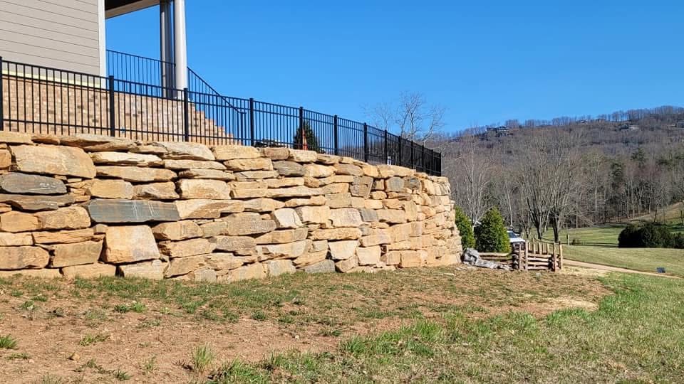 Black aluminum fence on top of a stone retaining wall
