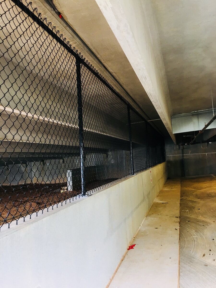Black chain link infill mounted along the concrete ledge of a parking deck interior