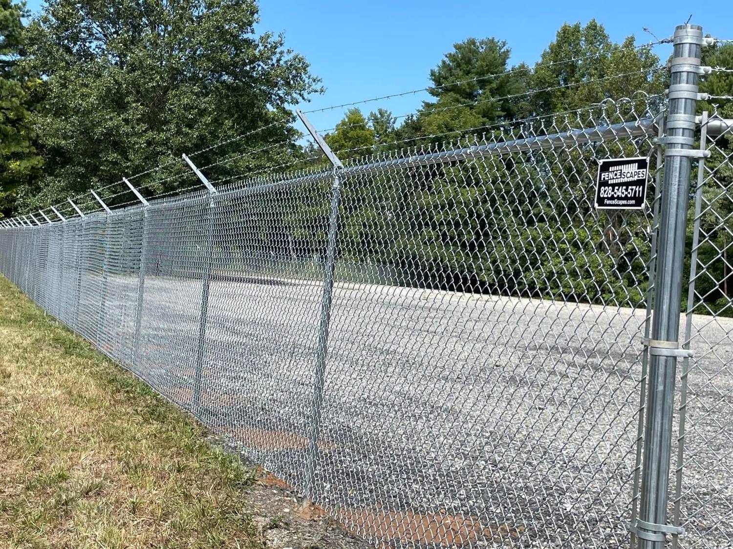 Galvanized chain-link fence with barbed arms around a commercial yard