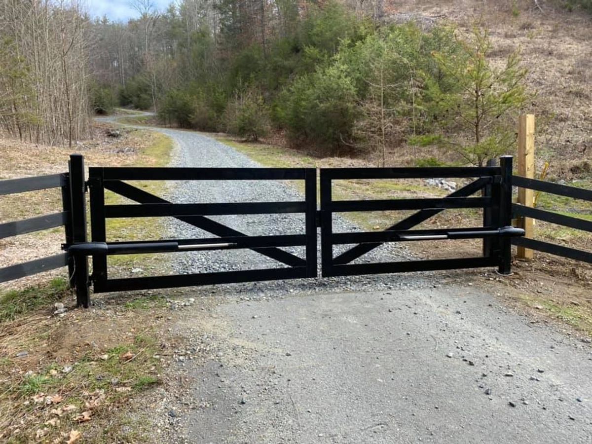 Black farm-style double gate on a gravel drive