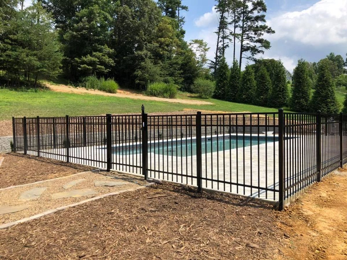 Black ornamental aluminum picket fence around an in-ground pool