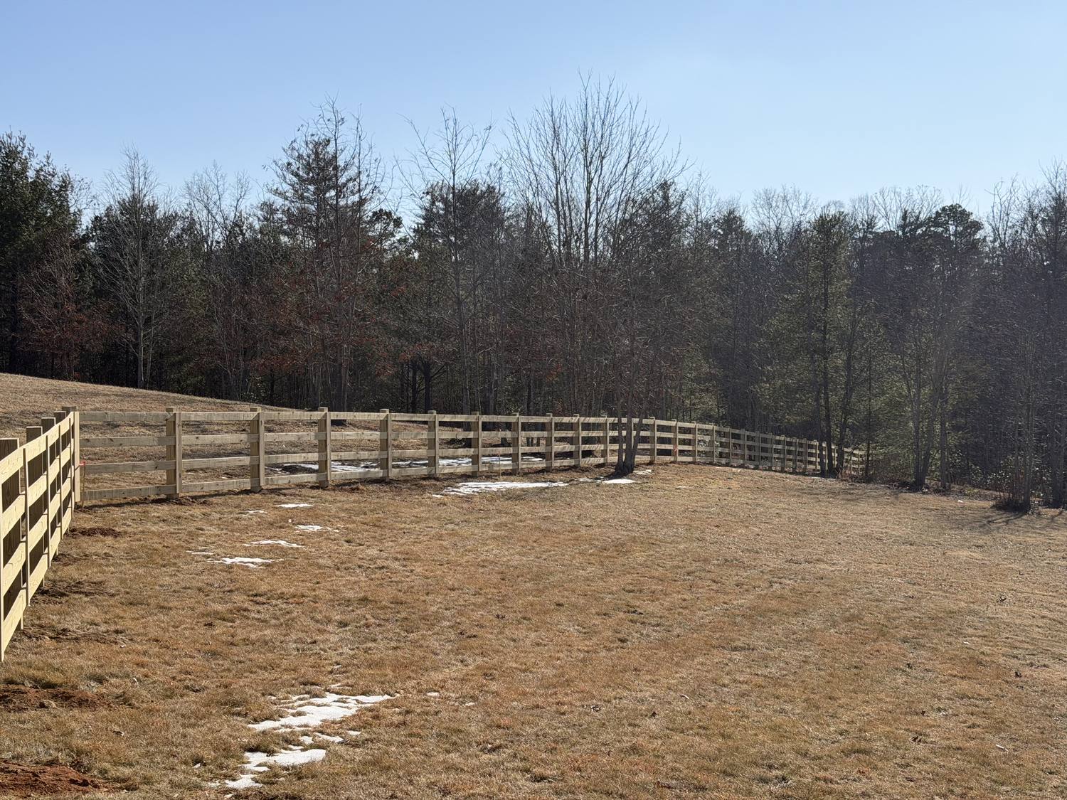 Four-rail wood fence around a wide pasture